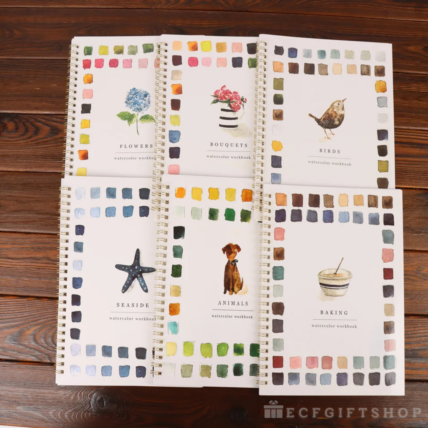 Set of watercolor workbooks with different themes on a wooden surface